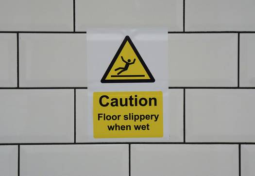 Person slipping on wet supermarket floor with caution sign
